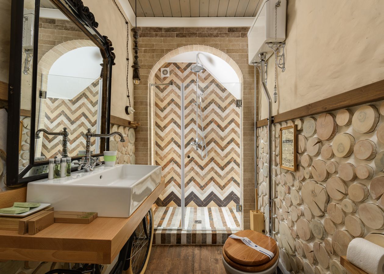 Herringbone tiling on a shower wall in a bathroom, with the zig-zag running vertically behind a glass screen