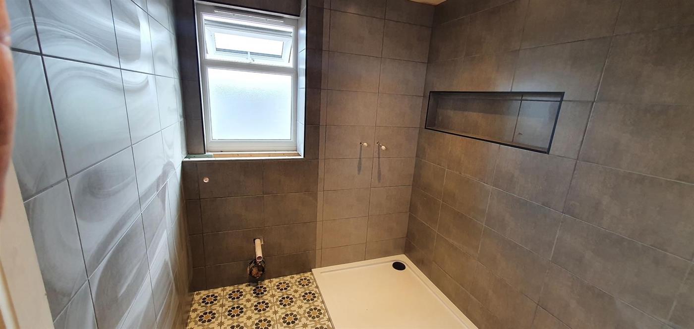 Shower room with patterned floor tiles by Kew Construction, Liverpool