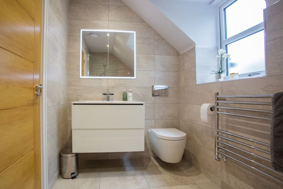 Timeless bathroom design with neutral tiling, walk-in shower and classic white suite — bathroom trends that date badly avoided
