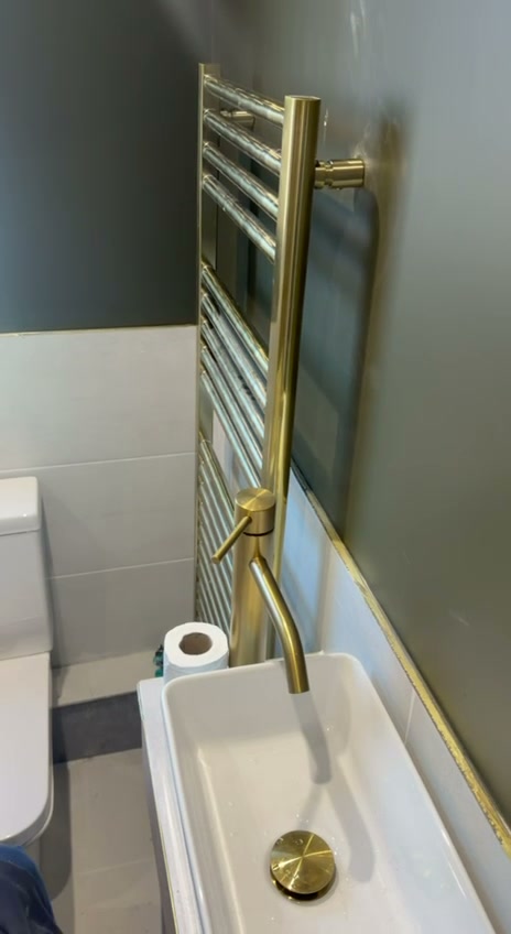 Brushed gold basin tap, gold click-clack waste and gold towel rail in a cloakroom, Liverpool