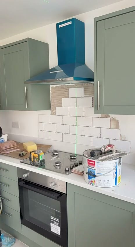 Kitchen splashback tiling in progress in Liverpool with white metro tiles in a brick bond and a laser level line